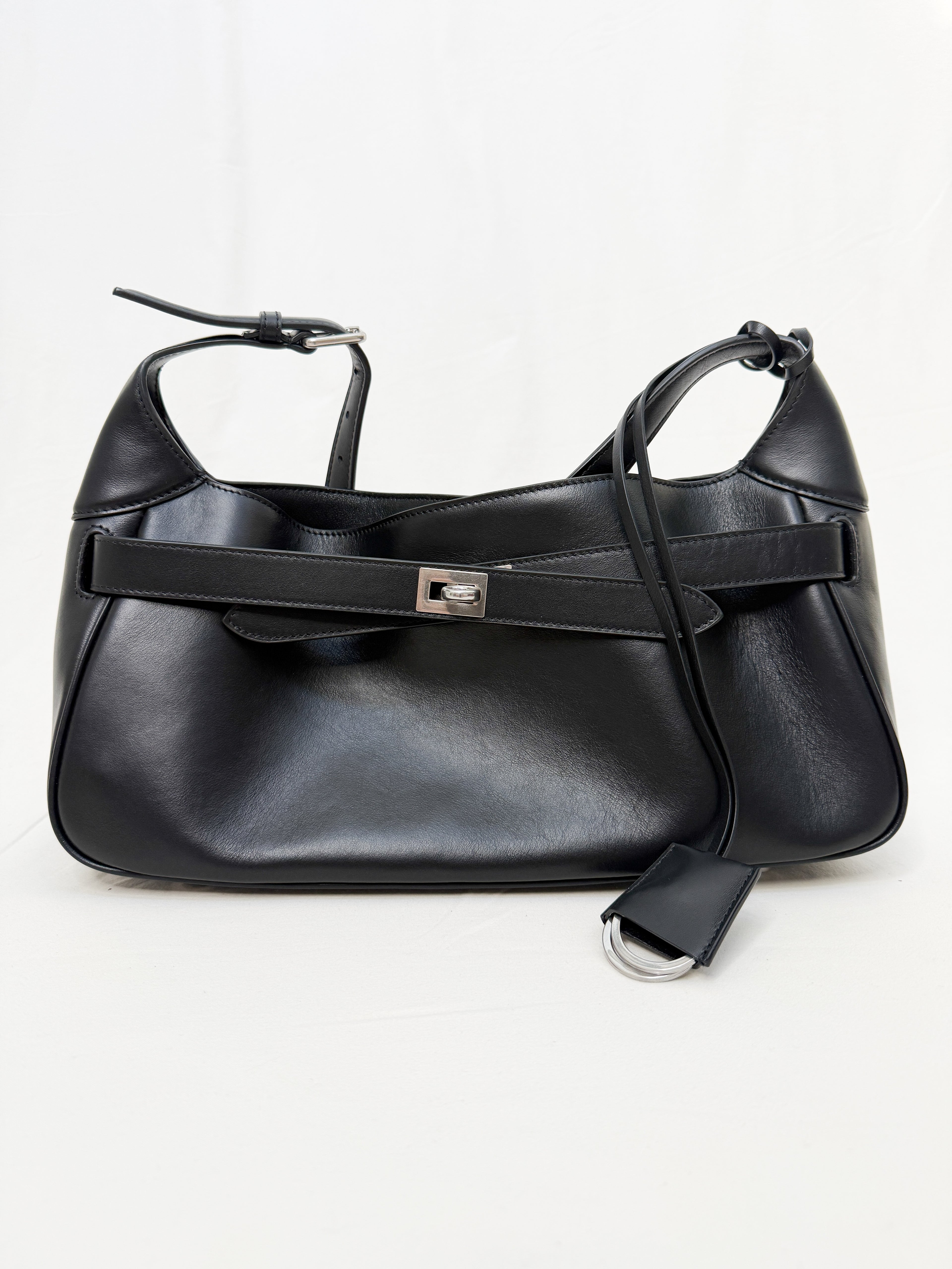 Black leather handbag with a strap on a white background