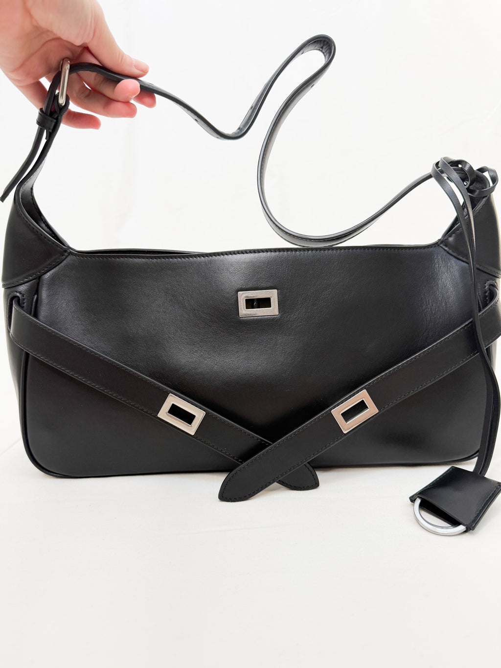 Black leather handbag with silver hardware on a white background