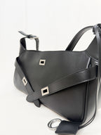 Black leather handbag with silver buckles on a white background