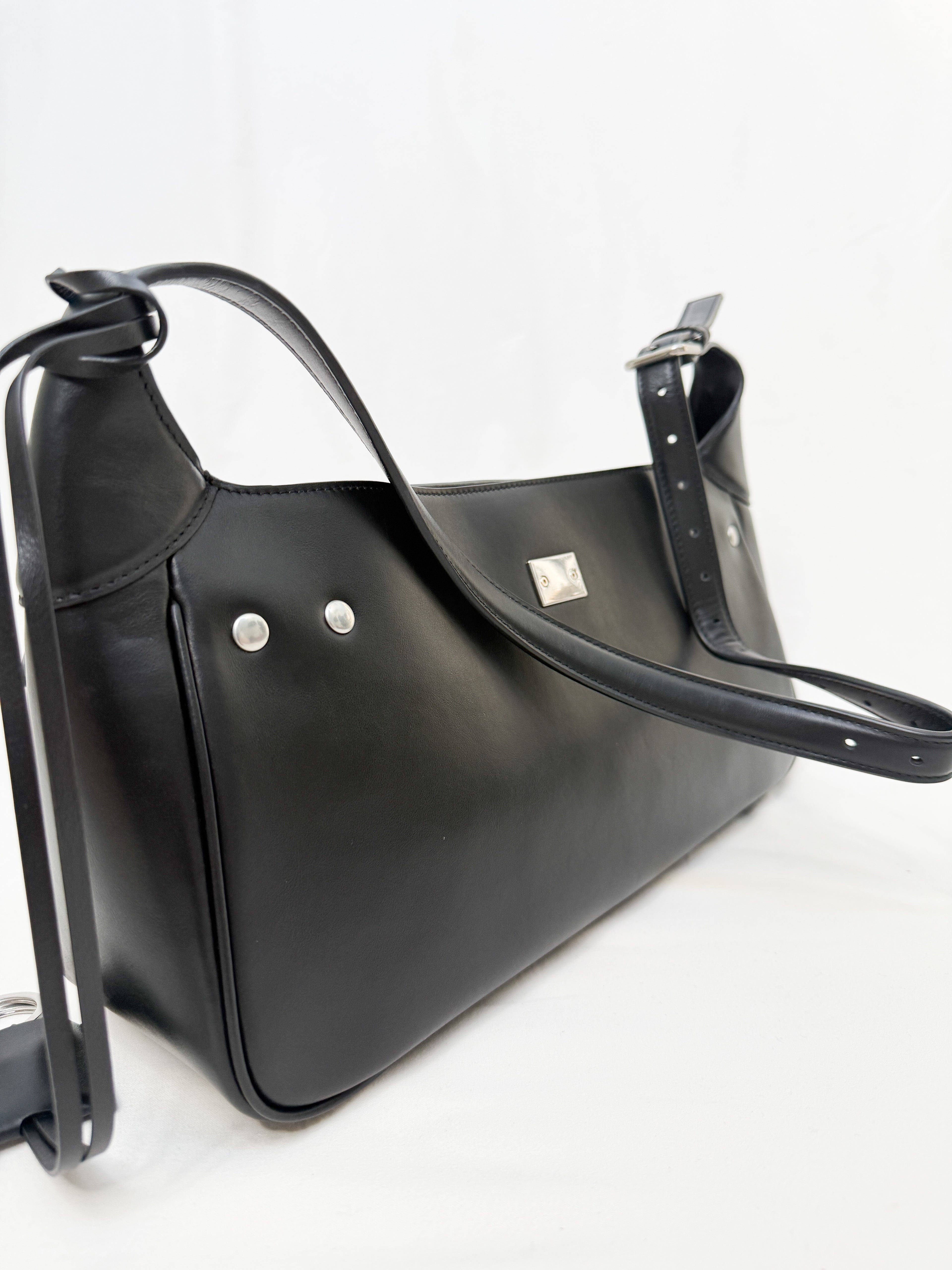Black handbag with silver hardware on a white background