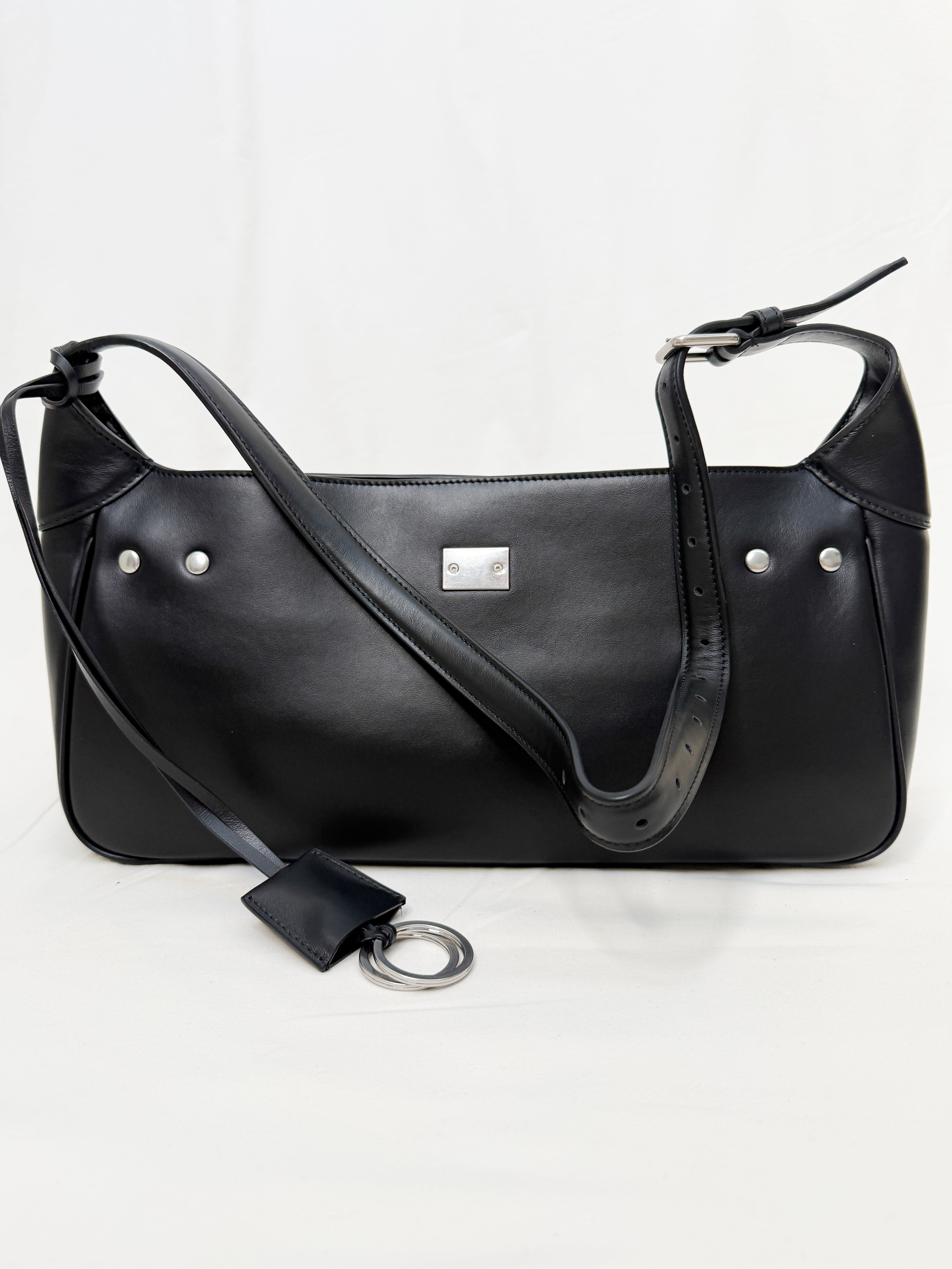 Black leather handbag with a shoulder strap on a white background