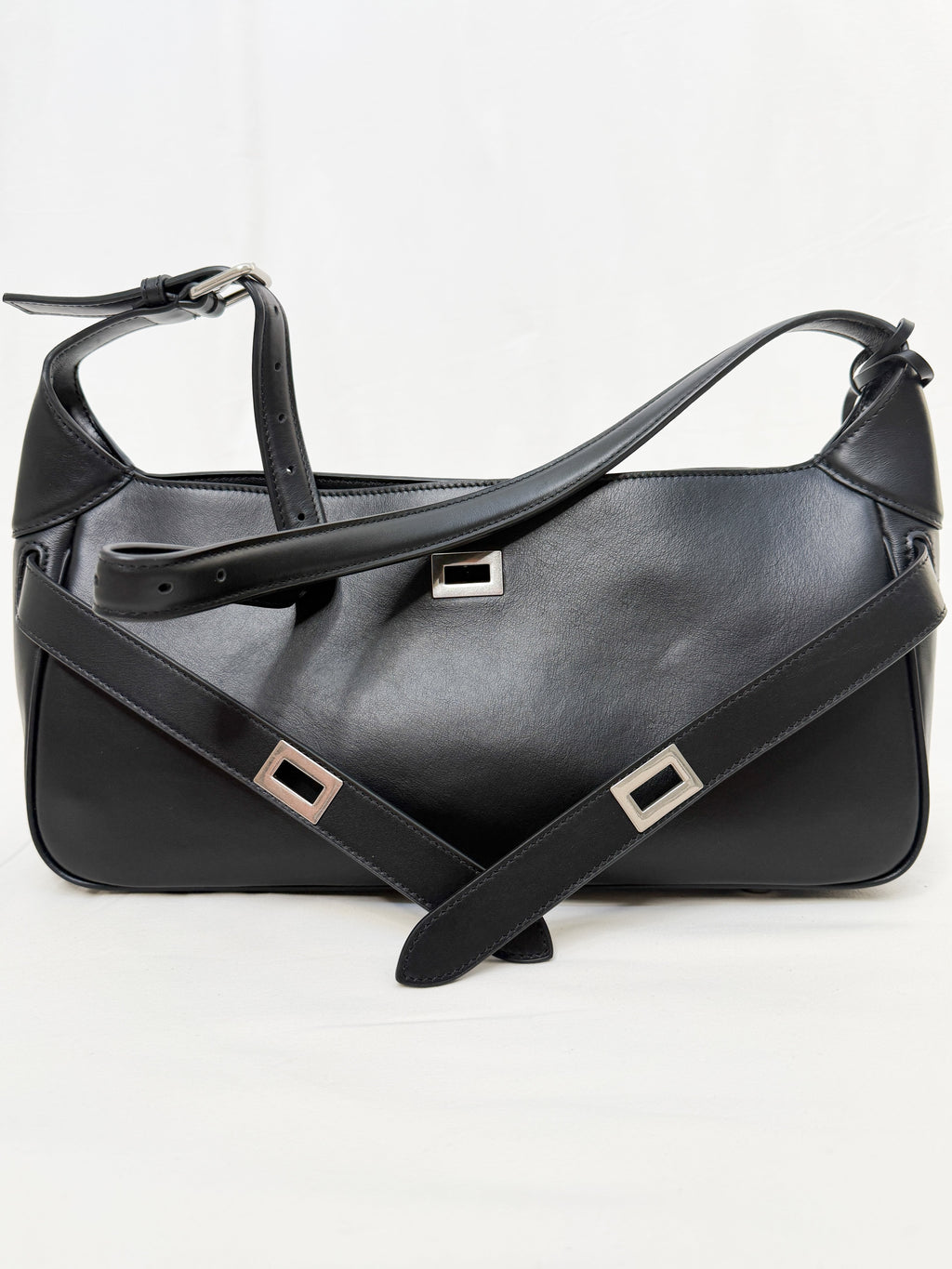 Black leather handbag with silver buckles on a white background