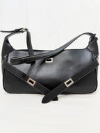 Black leather handbag with silver buckles on a white background