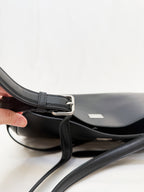 Close-up of a black handbag with a silver buckle on a white background