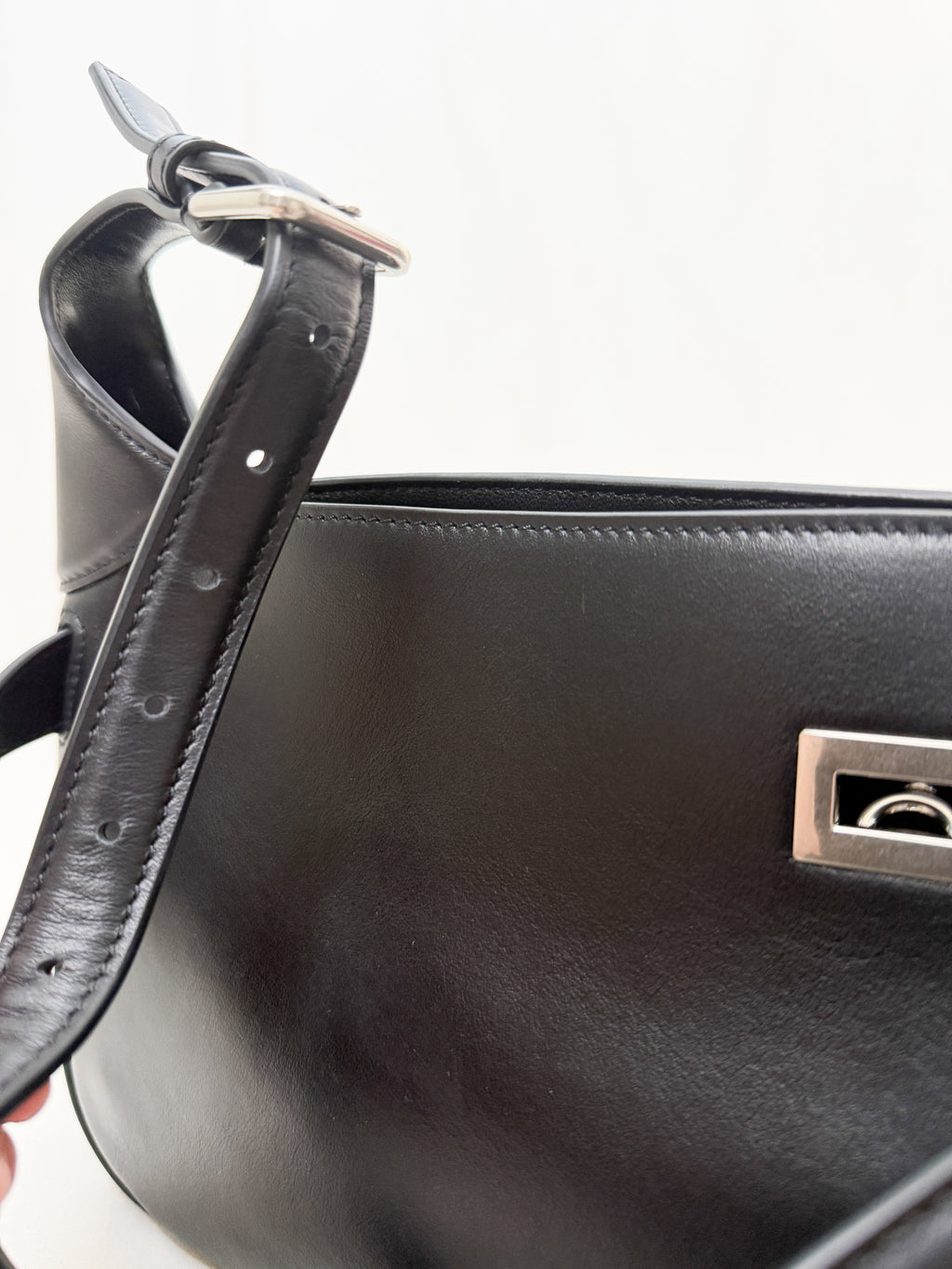Black handbag with a silver clasp on a white background