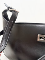 Black handbag with a silver clasp on a white background