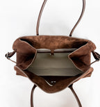 Brown leather handbag with a reflective interior on a white background