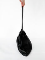 Black bag held by a hand on a white background