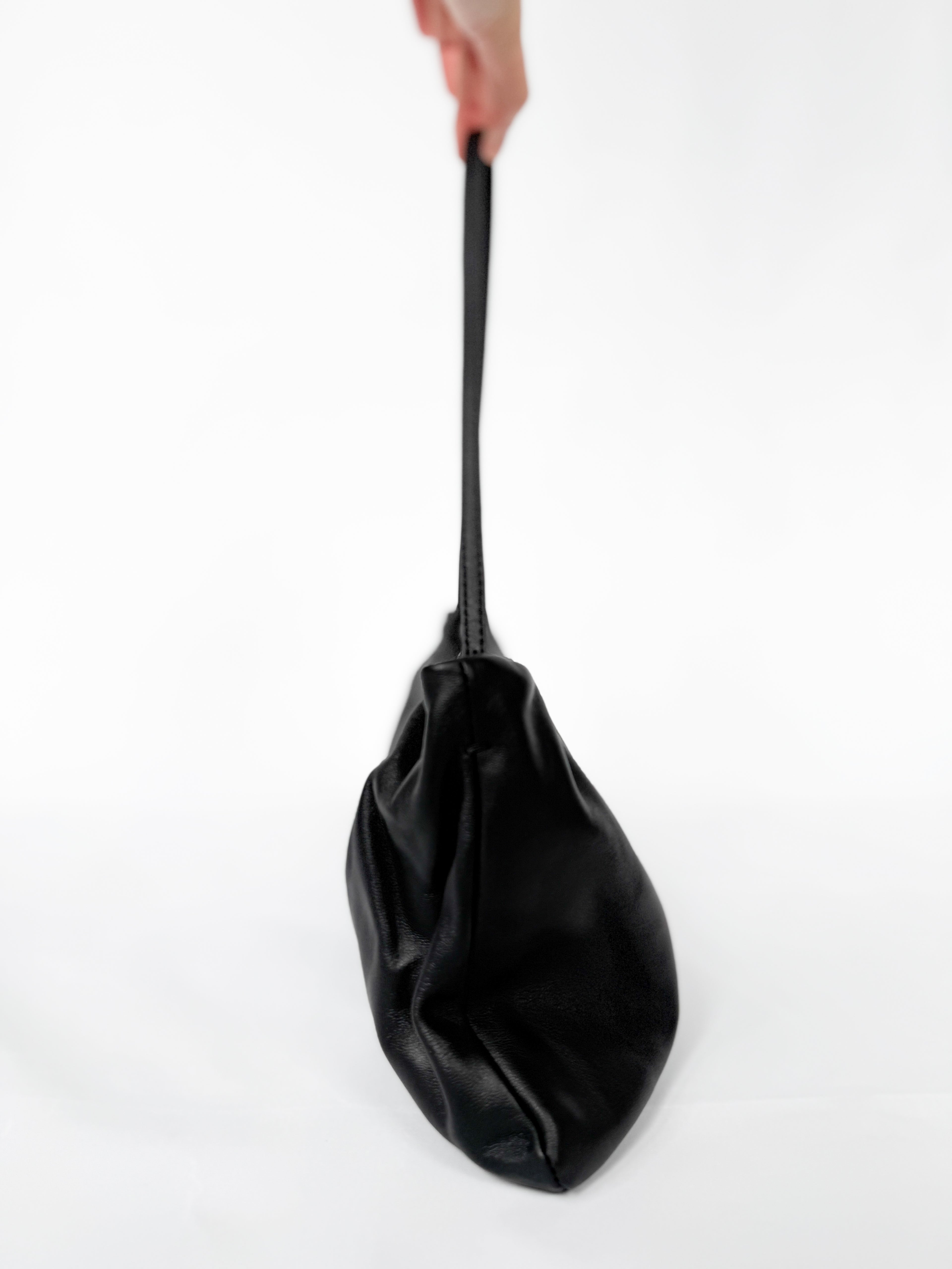 Black bag held by a hand on a white background